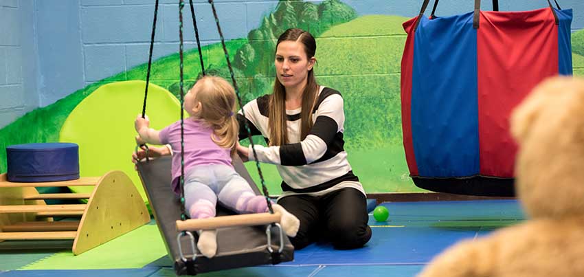 Physical Education MST student doing an exercise with a child on a swing